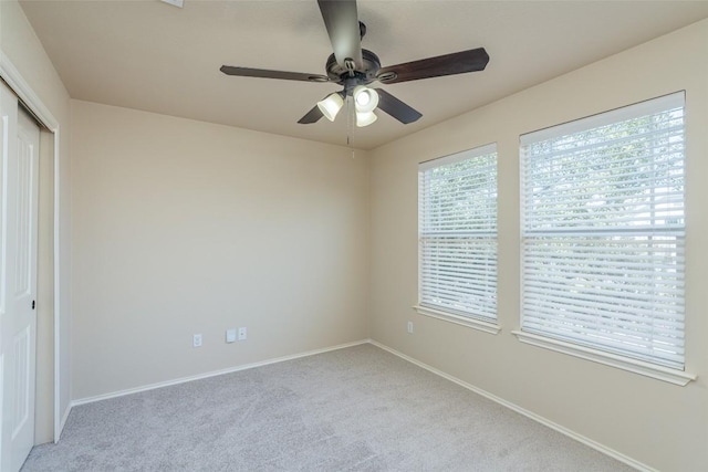 unfurnished bedroom with a closet, ceiling fan, light carpet, and baseboards