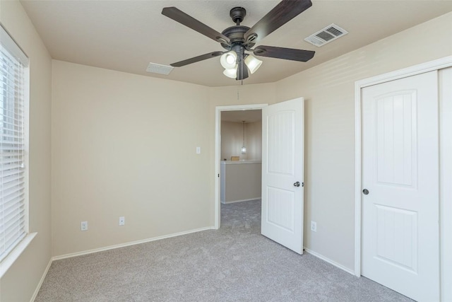 unfurnished bedroom featuring visible vents, baseboards, light colored carpet, and a closet