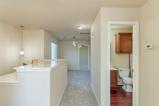 hallway with carpet, visible vents, and baseboards