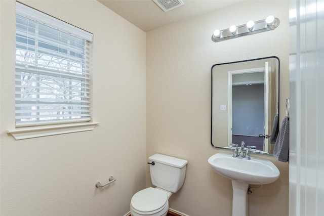 half bathroom with toilet, visible vents, and a sink