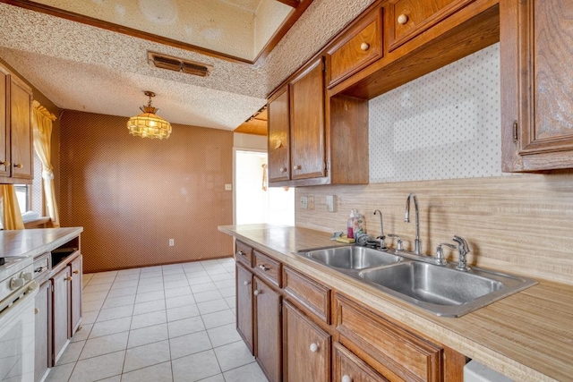 kitchen featuring a sink, light tile patterned flooring, brown cabinetry, light countertops, and white gas range