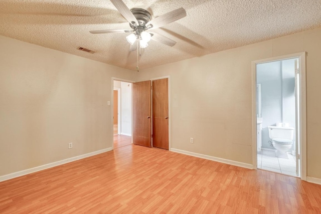 unfurnished room with a ceiling fan, baseboards, visible vents, light wood finished floors, and a textured ceiling