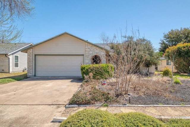 view of front of property with stone siding, an attached garage, and driveway