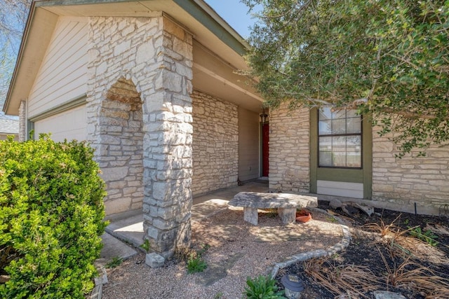 property entrance featuring stone siding and a garage