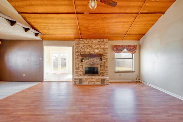 unfurnished living room featuring wood ceiling, lofted ceiling, and a stone fireplace