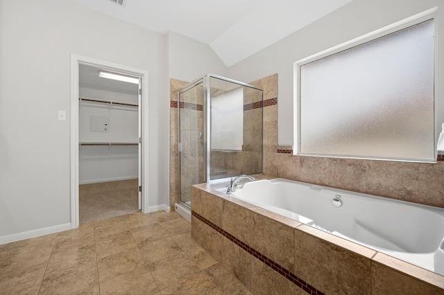 bathroom with a shower stall, a walk in closet, baseboards, vaulted ceiling, and a bath