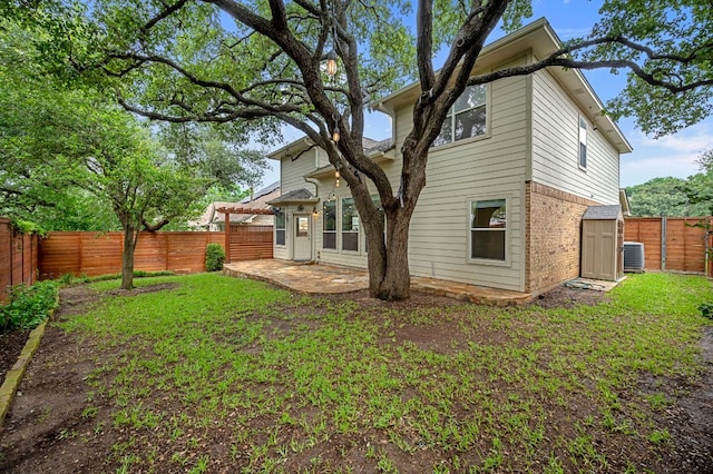 rear view of house featuring brick siding, central AC unit, a lawn, a fenced backyard, and a patio