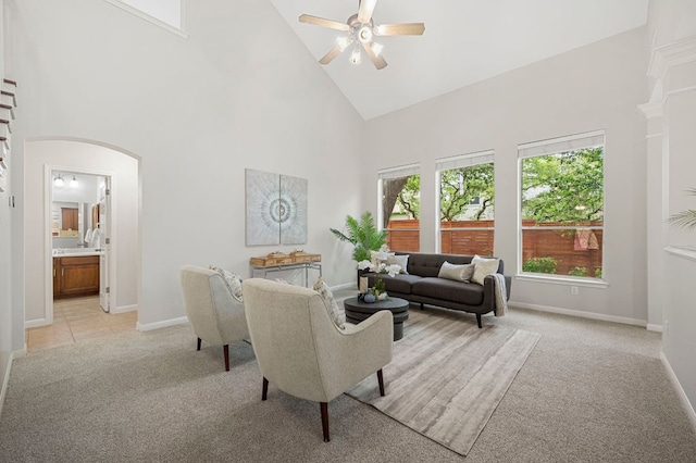 living room with ceiling fan, high vaulted ceiling, arched walkways, and light carpet