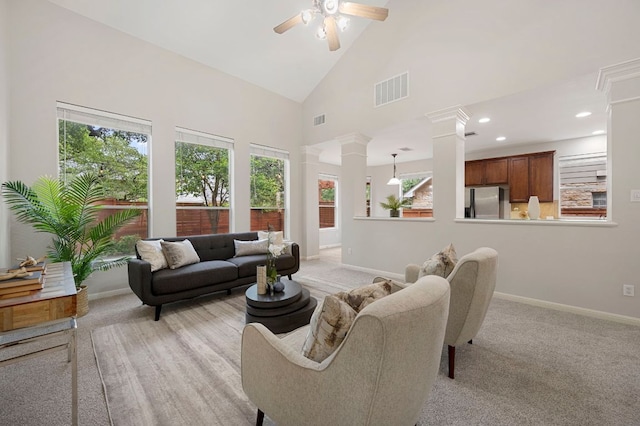 living room with visible vents, high vaulted ceiling, a ceiling fan, baseboards, and ornate columns