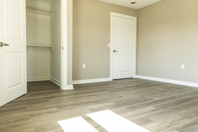 unfurnished bedroom featuring a closet, baseboards, and wood finished floors