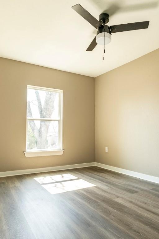 empty room featuring a ceiling fan, baseboards, and wood finished floors