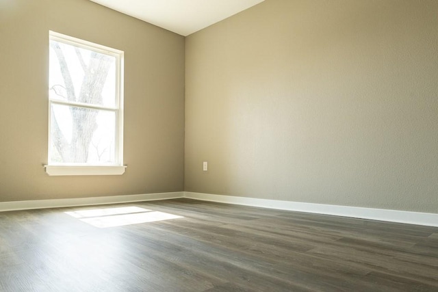 unfurnished room with baseboards and dark wood finished floors