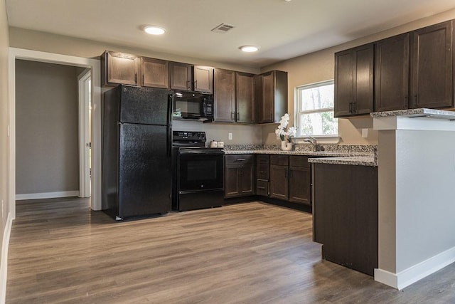 kitchen with visible vents, dark brown cabinets, baseboards, wood finished floors, and black appliances