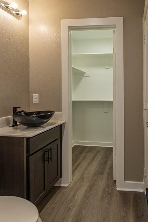 bathroom with baseboards, toilet, wood finished floors, and vanity