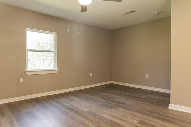 spare room featuring a ceiling fan, baseboards, visible vents, and dark wood-style flooring