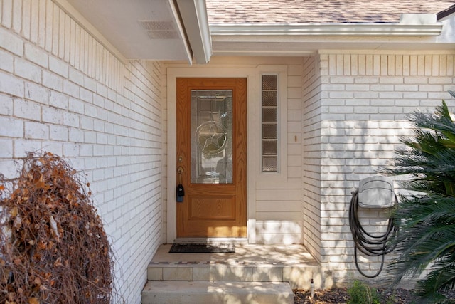 doorway to property featuring roof with shingles and visible vents