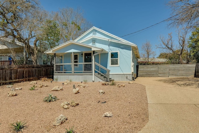 view of front of property with a porch, driveway, and fence