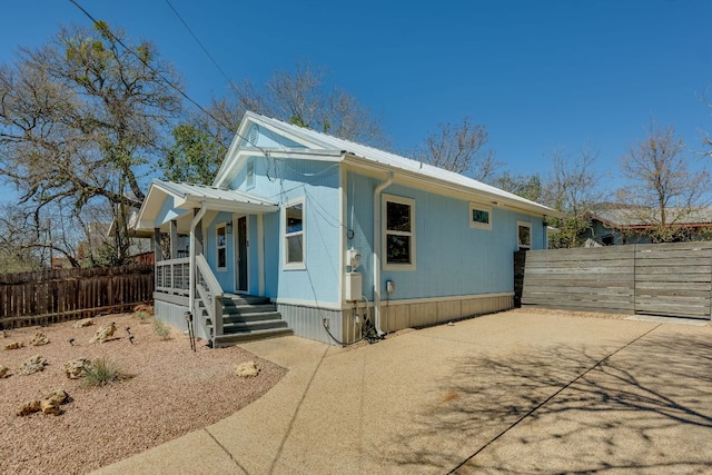 view of front of home with fence, covered porch, and metal roof