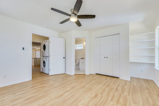 unfurnished bedroom with stacked washer and dryer, baseboards, and light wood-type flooring