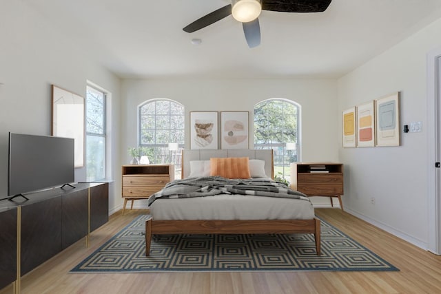 bedroom featuring light wood-style flooring, multiple windows, a ceiling fan, and baseboards