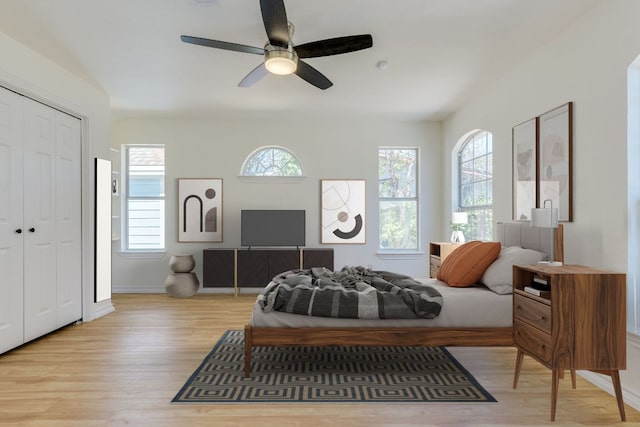 bedroom with light wood-style flooring, a ceiling fan, a closet, and baseboards