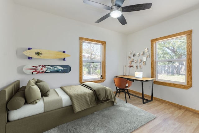 bedroom featuring baseboards, wood finished floors, and a ceiling fan