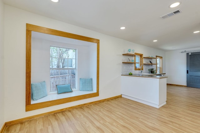 kitchen with tasteful backsplash, visible vents, light wood-style flooring, and open shelves