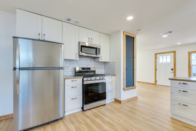 kitchen featuring decorative backsplash, light wood-style floors, visible vents, and stainless steel appliances