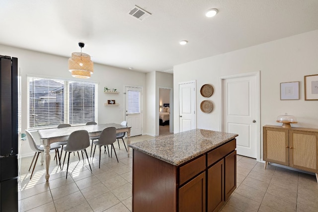 102 Tokalaun Dr, Hutto, TX 78634 - kitchen with freestanding refrigerator, light tile patterned floors, decorative light fixtures, a center island, and healthy amount of natural light