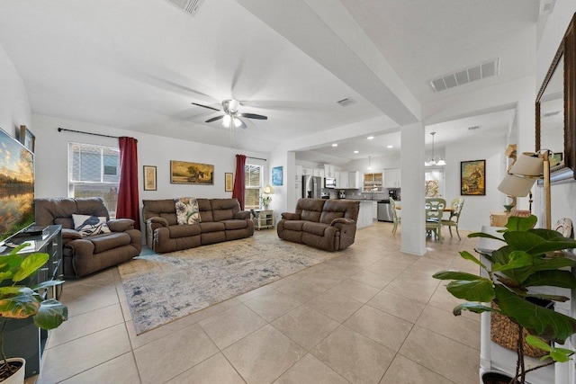 living room with light tile patterned floors, visible vents, and ceiling fan with notable chandelier