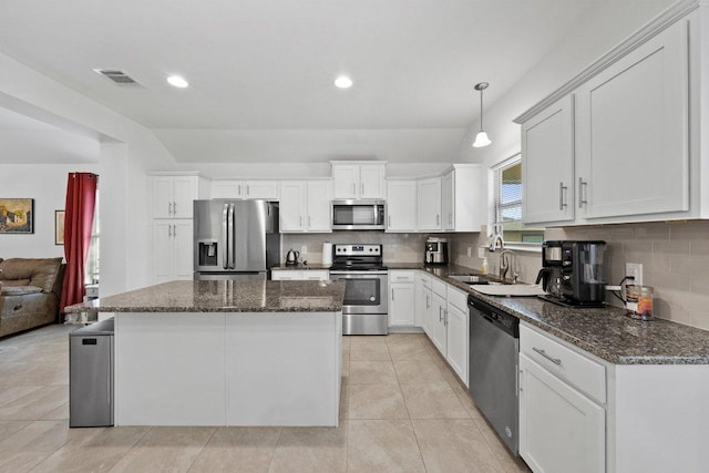 kitchen with visible vents, a kitchen island, a sink, stainless steel appliances, and backsplash