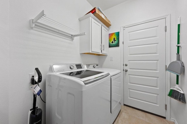 washroom featuring light tile patterned floors, cabinet space, and washing machine and dryer