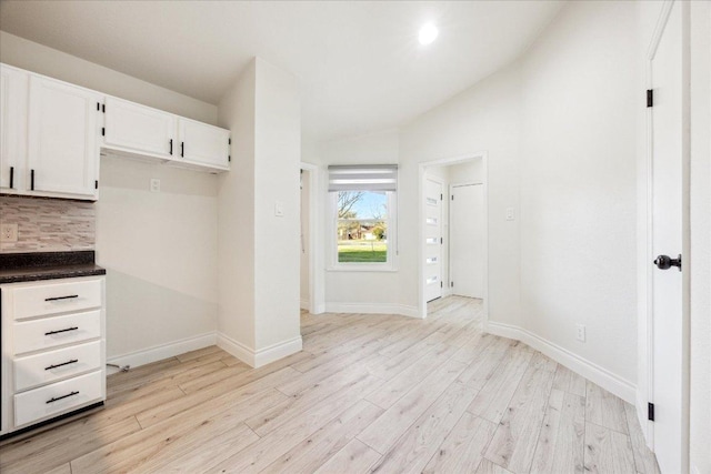 interior space with light wood finished floors, baseboards, and lofted ceiling