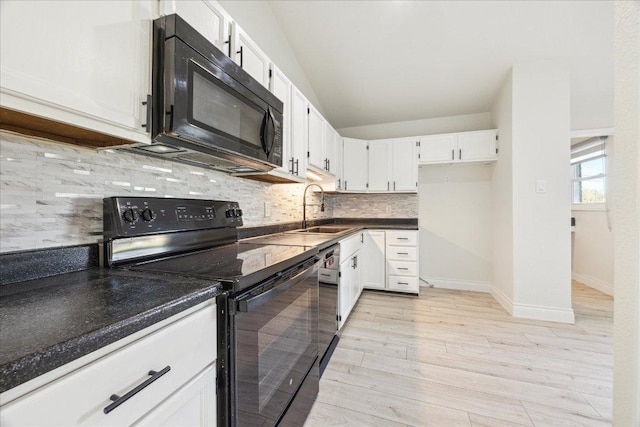 kitchen featuring dark countertops, light wood-style floors, white cabinets, black appliances, and a sink