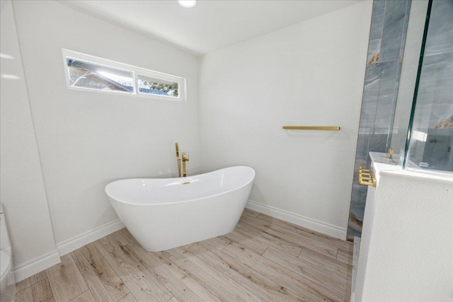 bathroom featuring a freestanding tub, wood finished floors, baseboards, and walk in shower