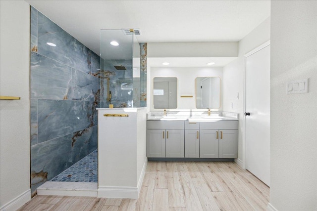 bathroom featuring wood finished floors, visible vents, double vanity, a sink, and walk in shower