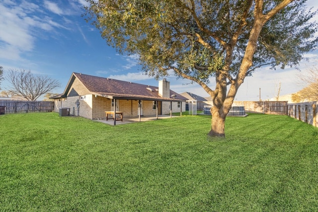 back of property with a yard, a patio, brick siding, and a fenced backyard