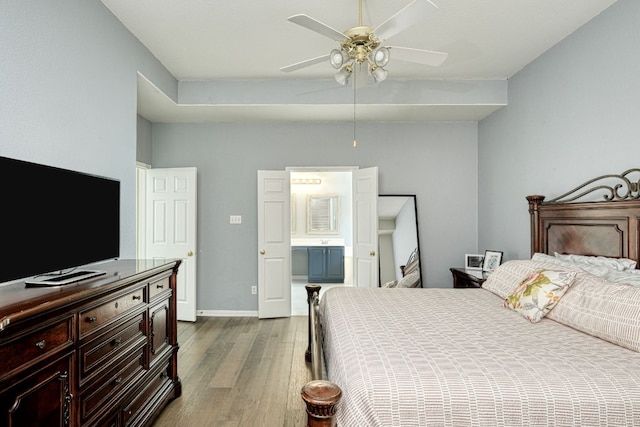 bedroom with ceiling fan, ensuite bath, dark wood-type flooring, and baseboards