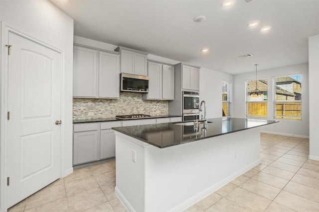 kitchen featuring dark countertops, gray cabinets, appliances with stainless steel finishes, and a sink