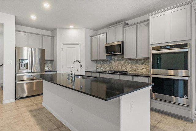 kitchen featuring dark countertops, gray cabinets, appliances with stainless steel finishes, and a sink