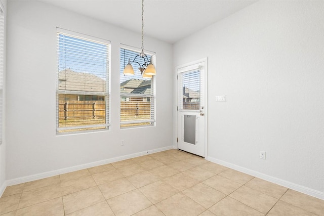 unfurnished dining area featuring an inviting chandelier, baseboards, and a wealth of natural light