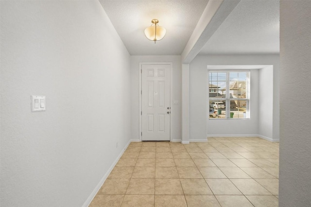 foyer entrance featuring light tile patterned flooring, a textured ceiling, and baseboards