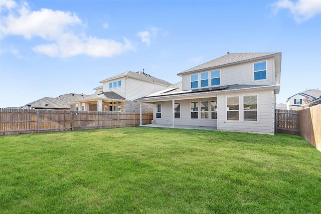 back of property featuring a yard, a patio, solar panels, and a fenced backyard