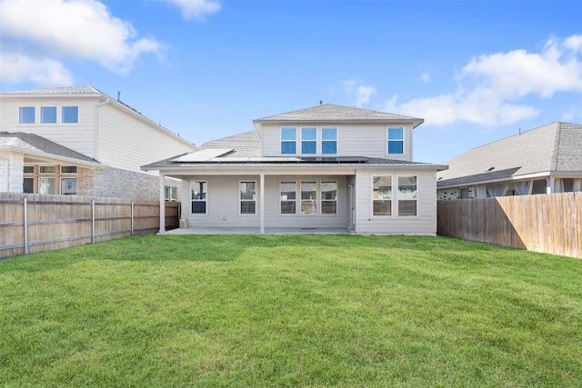 back of property with a lawn, solar panels, a fenced backyard, and a patio area