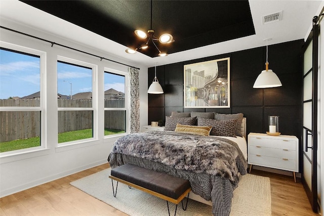 bedroom with visible vents, multiple windows, and wood finished floors