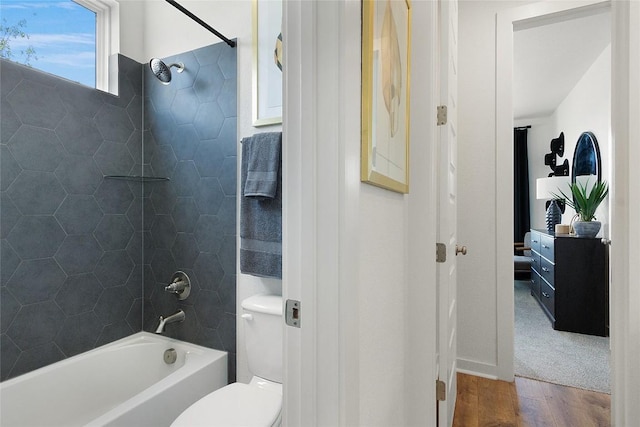 full bath with toilet, wood finished floors, and  shower combination