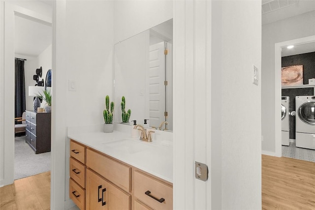 bathroom featuring wood finished floors, vanity, and washing machine and clothes dryer