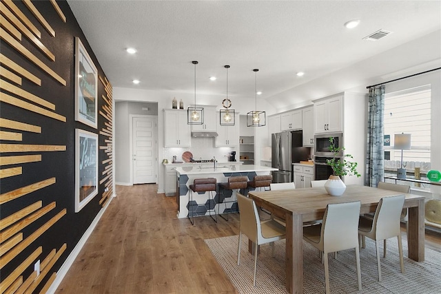 dining area featuring beverage cooler, recessed lighting, wood finished floors, and visible vents