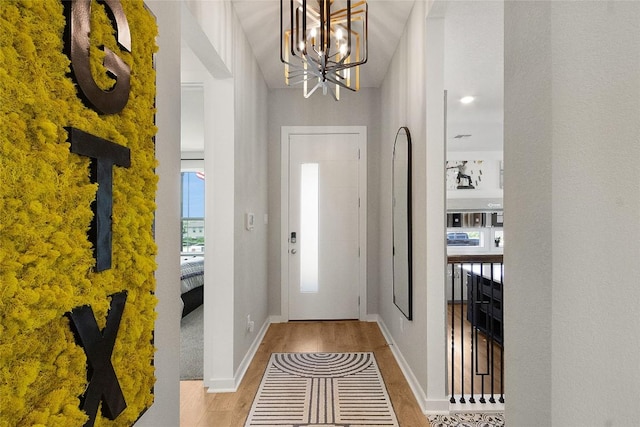 foyer entrance featuring a notable chandelier, baseboards, and wood finished floors