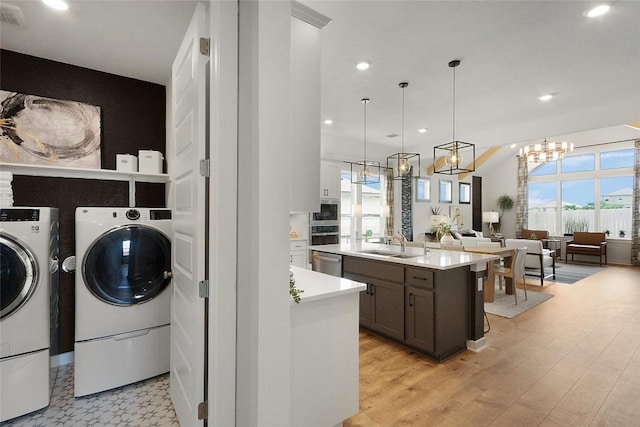 clothes washing area with laundry area, light wood-style flooring, recessed lighting, a sink, and independent washer and dryer